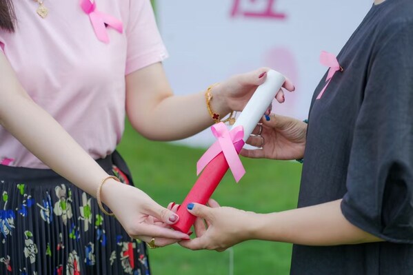 复旦学子代表把象征粉红力量的粉色接力棒传递给社会受助者